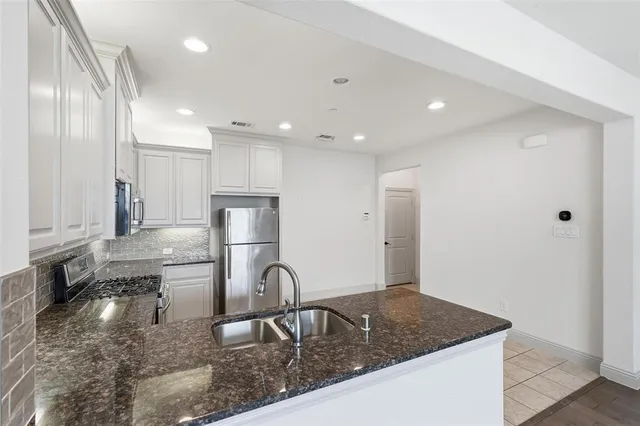 a kitchen with stainless steel appliances granite countertop a sink refrigerator and cabinets