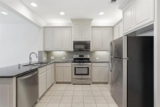 a kitchen with stainless steel appliances granite countertop a stove a sink and a refrigerator