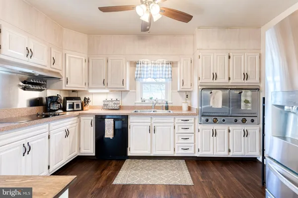 a kitchen with stainless steel appliances granite countertop a stove a sink and white cabinets
