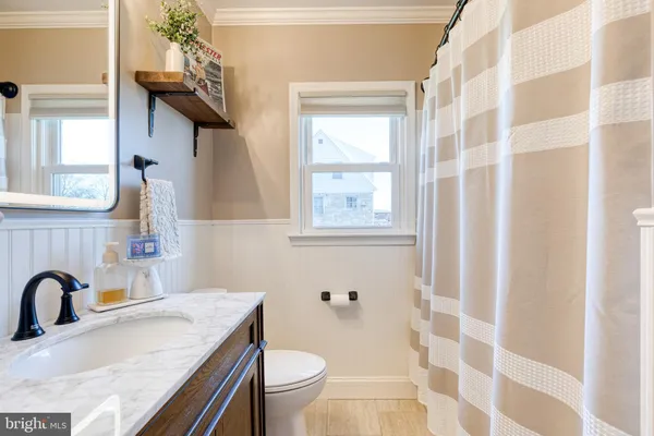 a bathroom with a granite countertop sink toilet a mirror and shower