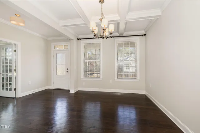 an empty room with wooden floor chandelier and windows