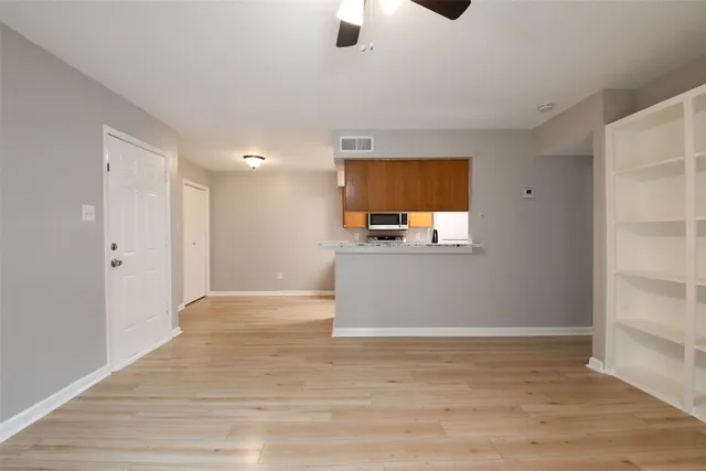 a view of kitchen and empty room with wooden floor