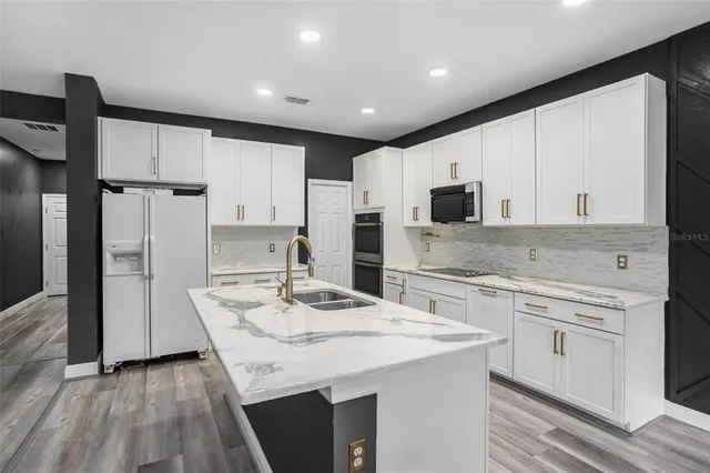 a kitchen with kitchen island granite countertop a sink appliances cabinets and counter space