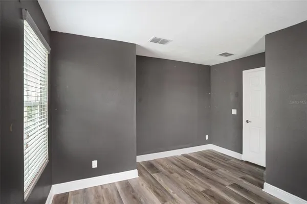 an empty room with wooden floor and windows