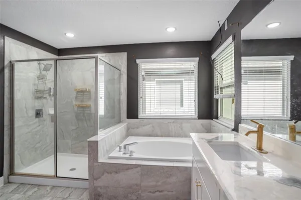 a spacious bathroom with a tub a sink and a large mirror