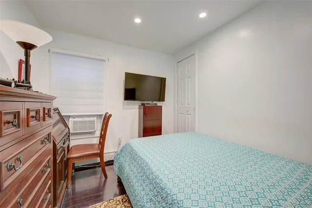 a bedroom with a bed a flat screen tv and chairs