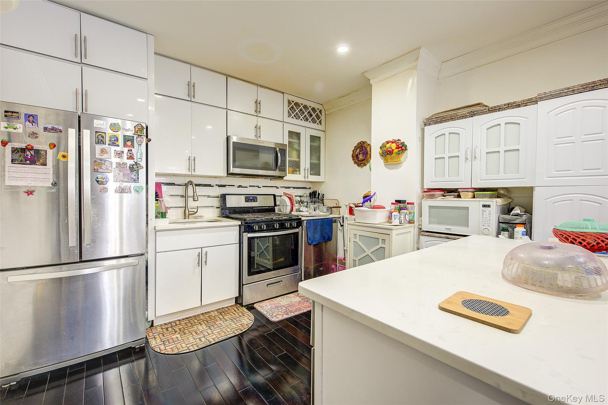 89-06 175th Street Queens, NY 11432 - Photo 9 of 29 Kitchen featuring stainless steel appliances, white cabinets, glass insert cabinets, dark wood-style flooring, and crown molding