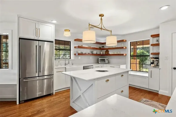 a kitchen with stainless steel appliances granite countertop a refrigerator a stove and a wooden floors