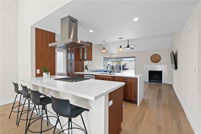 a large kitchen with granite countertop a stove a sink dishwasher and a fireplace with wooden floor