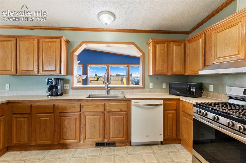 1350 South Calhan Highway Yoder, CO 80864 - Photo 25 of 45 Kitchen featuring wood cabinetry, light countertops, a stainless steel gas range, and a built-in dishwasher