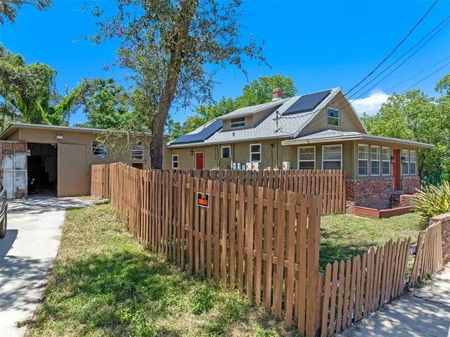 a view of a house with wooden fence next to a yard