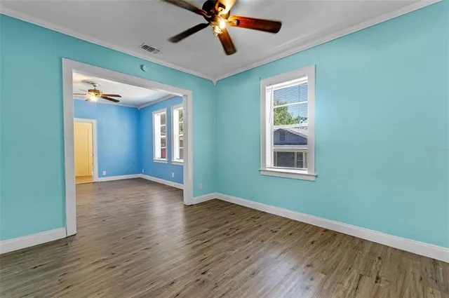 a view of an empty room with window and wooden floor