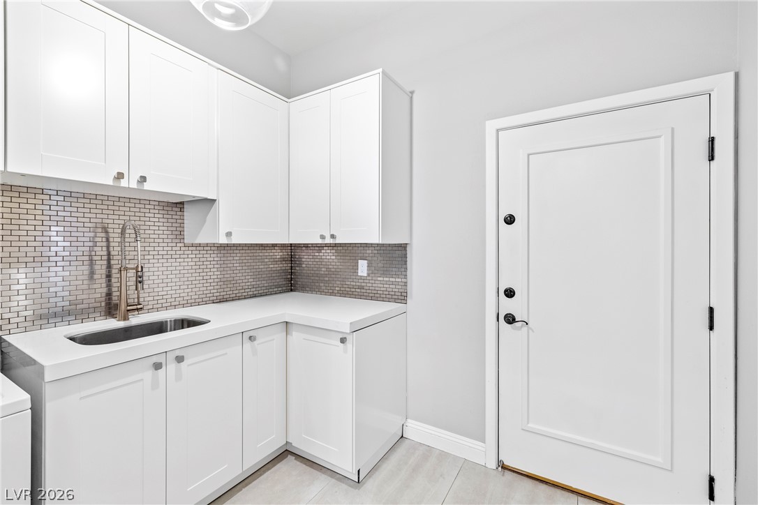 2000 Grouse Street Las Vegas, NV 89134 - Photo 28 of 89 A well-appointed laundry room features pristine white cabinetry and sleek metallic tile backsplash.