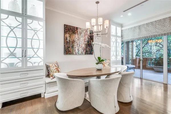 a dining room with wooden floor a chandelier a glass table and chairs