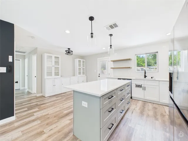 a large white kitchen with kitchen island a stove a sink dishwasher and a oven with white cabinets