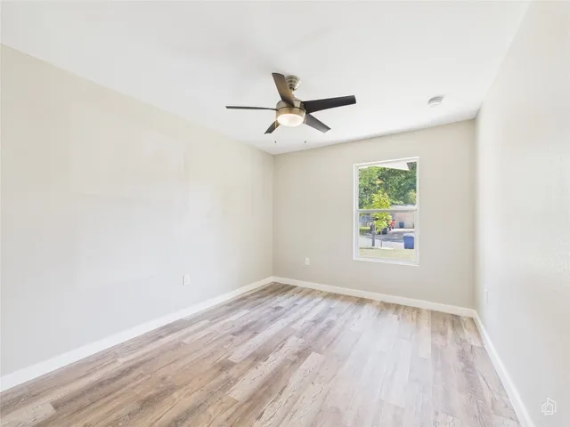an empty room with a window and a ceiling fan