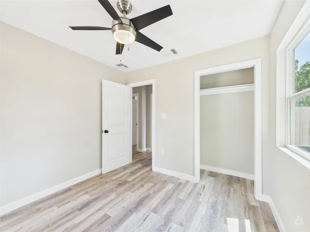 a view of empty room with wooden floor and fan