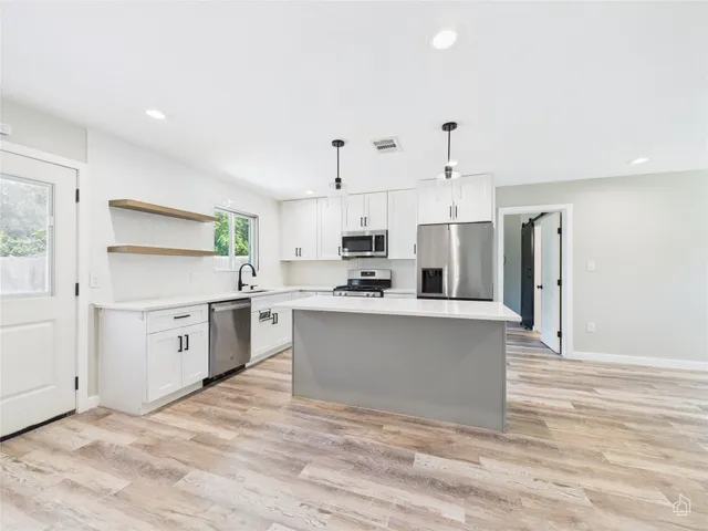 a kitchen with stainless steel appliances white cabinets and wooden floors