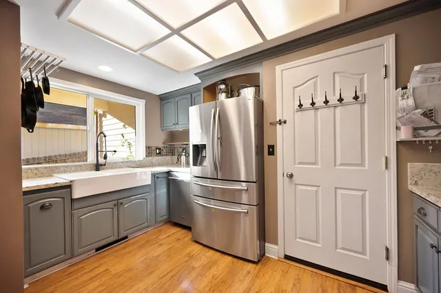 a kitchen with stainless steel appliances granite countertop a sink cabinets and wooden floor
