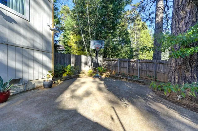 a view of a backyard with table and chairs plants and trees