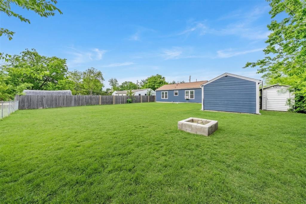 1802 Keneipp Road Carrollton, TX 75006 - Photo 21 of 22 The property features an expansive lawn, a fire pit, and a shed