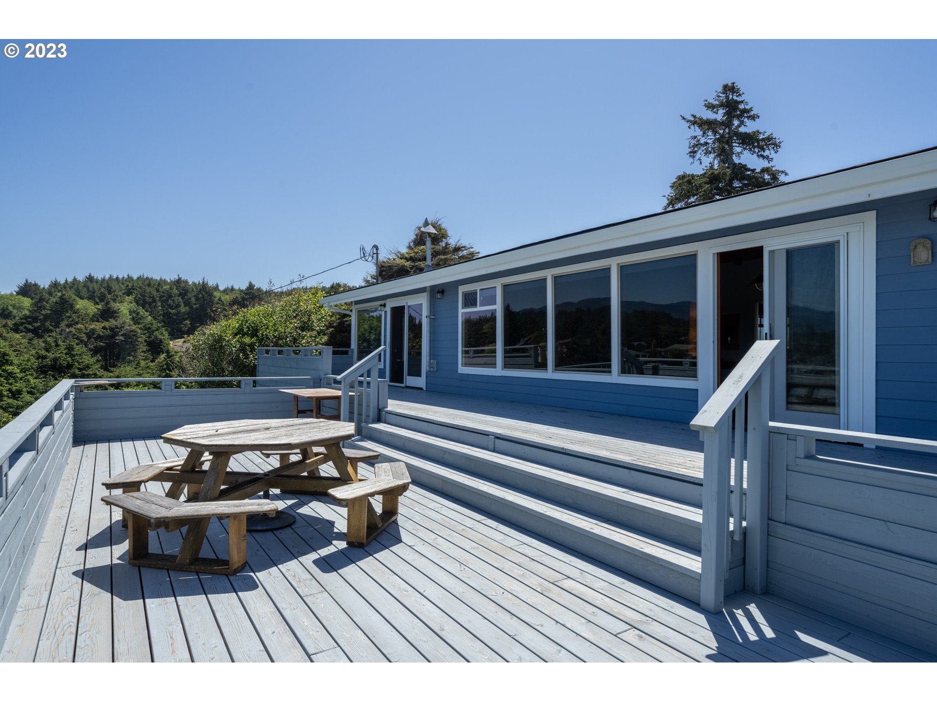 5430 2nd Street Northwest Tillamook, OR 97141 - Photo 30 of 48 a view of a roof deck with table and chairs a barbeque with wooden floor and fence