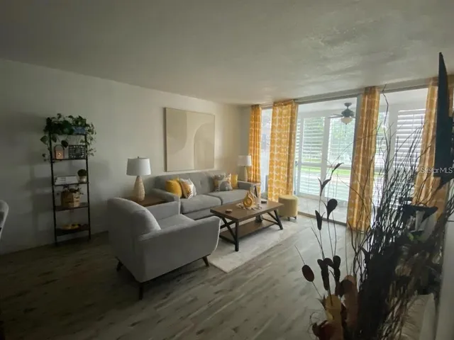 a living room with furniture a large window and wooden floor
