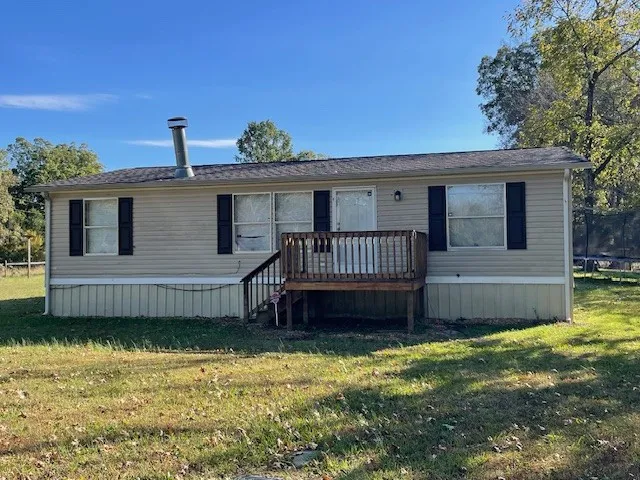 a view of a house with a wooden deck and a yard