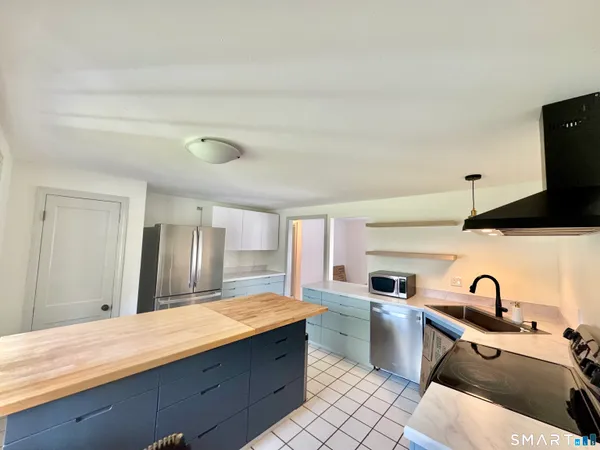 a large kitchen with stainless steel appliances kitchen island a stove a sink dishwasher a refrigerator and wooden cabinets with wooden floor