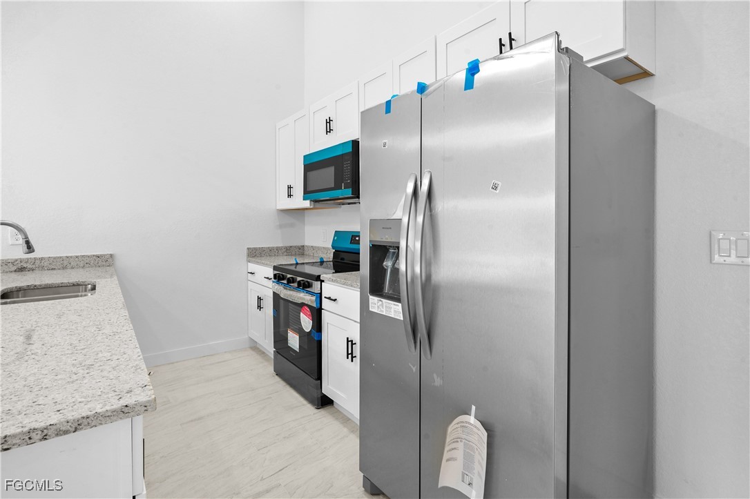 634 Knapp Street Lehigh Acres, FL 33974 - Photo 13 of 29 a kitchen with a refrigerator and a sink