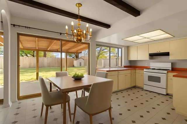 a view of a dining room with furniture a chandelier and kitchen view