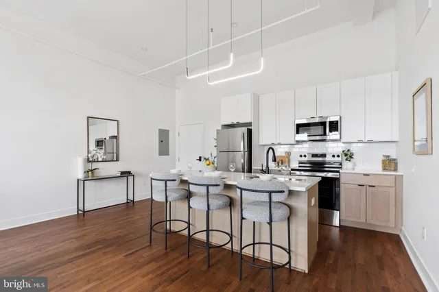 a kitchen with stainless steel appliances a dining table chairs microwave and sink