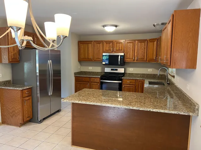 a kitchen with stainless steel appliances granite countertop a sink a stove and a refrigerator