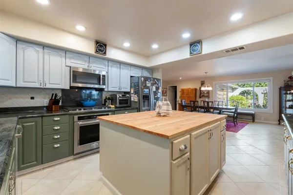 a kitchen with kitchen island granite countertop a stove top oven a sink a counter top space and cabinets