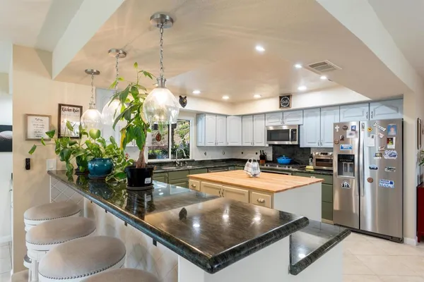 a kitchen with stainless steel appliances granite countertop a sink a stove and a refrigerator