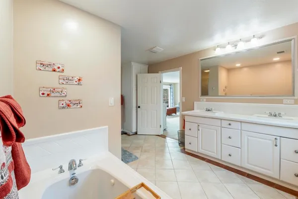a spacious bathroom with a tub sink and mirror