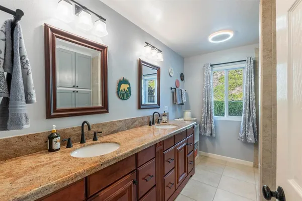 a bathroom with a granite countertop double vanity sink and a mirror