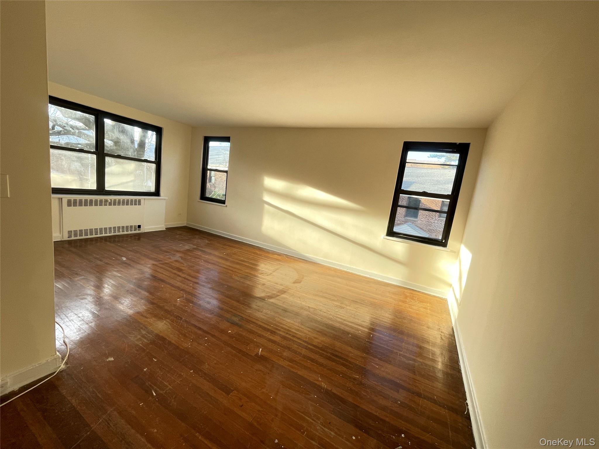141 East Hartsdale Avenue, Unit 2A Hartsdale, NY 10530 - Photo 4 of 24 Spare room with dark wood-type flooring, radiator heating unit, and healthy amount of natural light