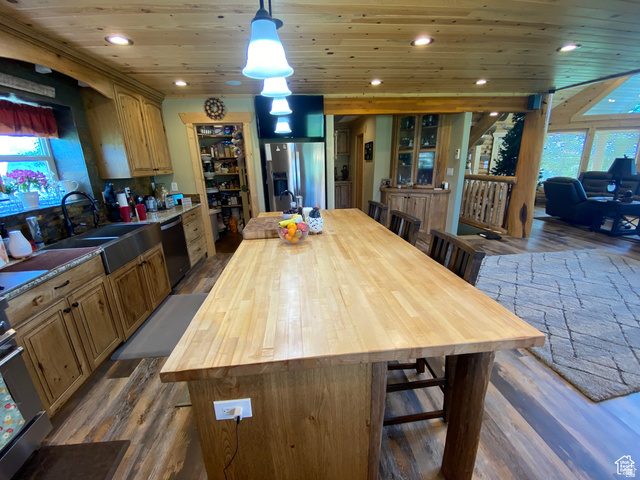 79 Auburn Forest Road Auburn, WY 83111 - Photo 25 of 76 Kitchen with butcher block counters, dark wood-type flooring, a breakfast bar, a kitchen island with sink, and wooden ceiling