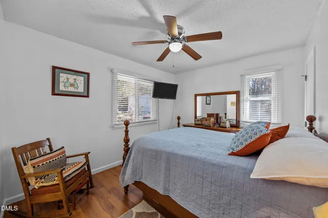 a view of a bedroom with wooden floor and fan