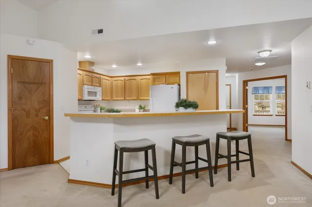 a kitchen with kitchen island a dining table chairs cabinets and stainless steel appliances