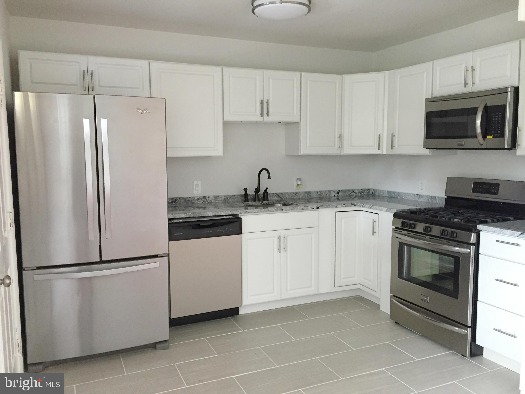 5705 Westgate Road Lanham, MD 20706 - Photo 5 of 26 a white kitchen with stainless steel appliances granite countertop a refrigerator stove a sink and dishwasher