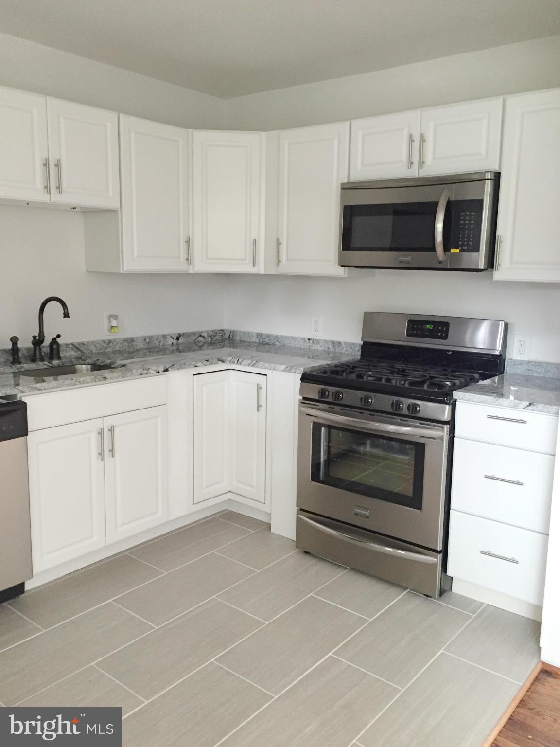 5705 Westgate Road Lanham, MD 20706 - Photo 6 of 26 a kitchen with granite countertop white cabinets and appliances