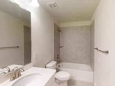 a bathroom with a bathtub shower sink vanity mirror and toilet
