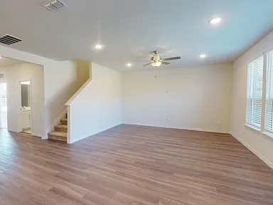 a view of an empty room with wooden floor and a window