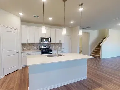 a large kitchen with granite countertop a stove top oven a sink a counter space and cabinets