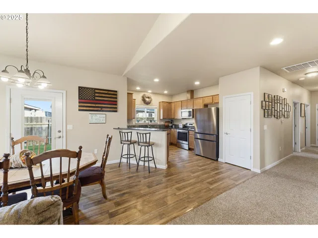 a kitchen with stainless steel appliances kitchen island granite countertop a table chairs and a refrigerator