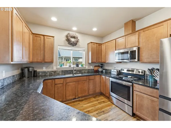 a kitchen with stainless steel appliances granite countertop a stove top oven a sink dishwasher a refrigerator and a microwave