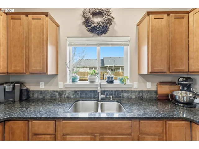 a kitchen with granite countertop a sink a window and cabinets