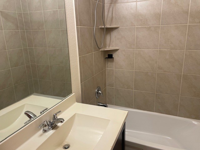 10201 Gertrudis Loop Austin, TX 78747 - Photo 9 of 24 Functional full bathroom featuring neutral tile, a built-in tub, and a vanity with an integrated sink.